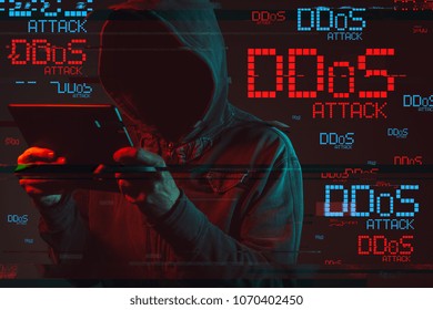 Distributed denial of service or DDoS attack concept with faceless hooded male person using tablet computer, low key red and blue lit image and digital glitch effect