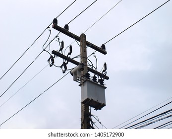 Distribution transformer on the pole: convert high voltage energy into low voltage and supply electricity through the power cable to the service recipients. On the dark sky background of rain clouds.