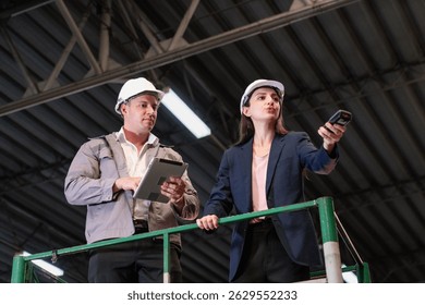 Distribution warehouse manager and client businesswoman using digital tablet checking inventory storage on shelf. Storehouse business worker and logistic engineer standing together at storage service