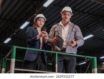 Distribution warehouse manager and client businesswoman using digital tablet checking inventory storage on shelf. Storehouse business worker and logistic engineer standing together at storage service