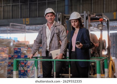 Distribution warehouse manager and client businesswoman using digital tablet checking inventory storage on shelf. Storehouse business worker and logistic engineer standing together at storage service