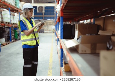 Distribution warehouse worker using digital tablet checking inventory storage on shelf. Female merchandise supervisor, logistic engineer working at storage room in storehouse. Goods supply management