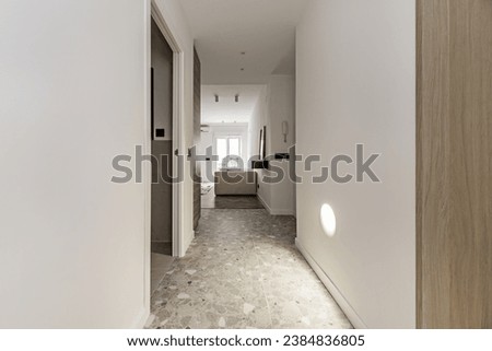 Distributor hallway of a modern house with gray terrazzo floor, smooth white painted walls