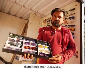 DISTRICT KATNI, INDIA - MARCH 02, 2022: An Indian Street Male Shop Keeper With Beard Presenting Sun Glasses Collection Box On Hand