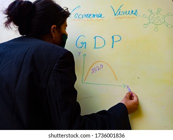 District Katni, Madhya Pradesh, India - May 17, 2020: An Indian Female Teacher Presenting World GDP During Coronavirus Impact On With Chalk Board. 