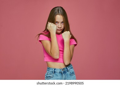 Distrustful child girl stands in defense stance with clenched fists. Battle, protection, domestic violence problem