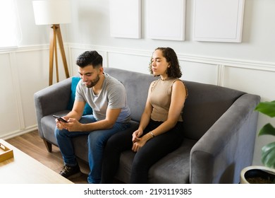 Distrustful Girlfriend Spying On Her Happy Boyfriend Texting On The Smartphone And Suspecting Of An Online Cheating Affair