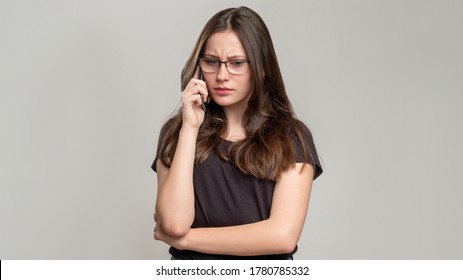 Disturbing Call. Distant Conflict. Troubled Woman Worried About Misunderstanding On Phone Isolated On Gray. Annoyed Lady Concerned About Negative Conversation.