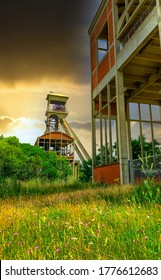 A disused coal mine pithead winding gear of an old Belgian coal mine shaft against a dramatic sunset sky