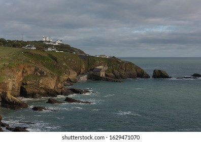 Disused Lifeboat Station with Lizard Lighthouse in the Background by the English Channel at Lizard Point on the South West Coast Path and Southern Tip of Cornwall, England, UK