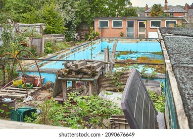 Disused Swimming Pool, Becoming Overgrown With Weeds, With Run Down Equipment And Changing Rooms