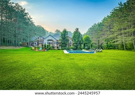 Dive into luxury with this stunning photo featuring a lavish swimming pool, exquisite house, lush green backyard, and meticulously designed garden. Experience the pinnacle of opulence and tranquility.