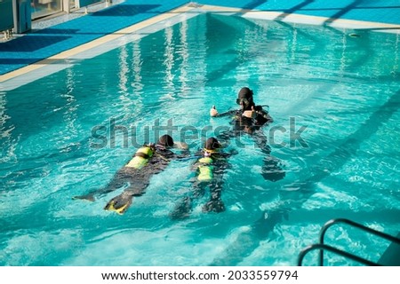 Divemaster and divers in aqualungs, dive course