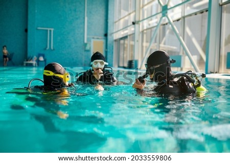 Divemaster and divers in aqualungs, diving school