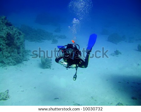 Diver with camera in deep and bubbles. Underwater photographer