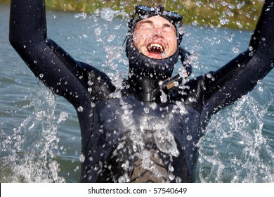 Diver In  Diving Suit With Splashes Of Jumping Out Of  Water And Gasping For Air