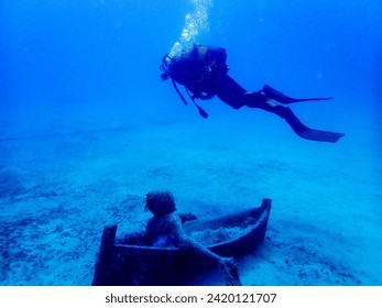 Diver explores the mesmerizing world beneath Lanzarote's azure waves, captivated by an underwater sculpture