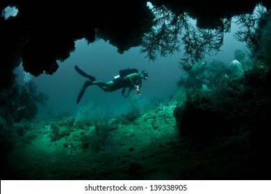 A Diver Explores The Mouth Of A Deep Cave In Raja Ampat, Indonesia.  This Area Is Known For Its High Marine Diversity And Great Scuba Diving.