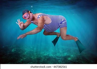 Diver in retro swimsuit swims underwater and shows gesture O.K. Swimmer examines the seabed. Vacation at sea. Man snorkeling in the tropical sea. Vintage style man with flippers diving under water.