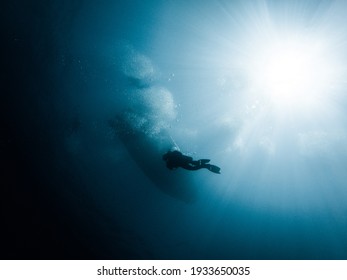 Diver in the sea under a boat