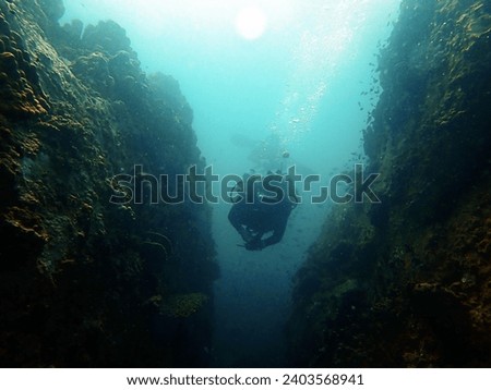 diver swimming through a narrow rock gaps in the sea