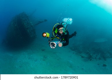 Diver with underwater video camera dives near the wreck, Red Sea.
