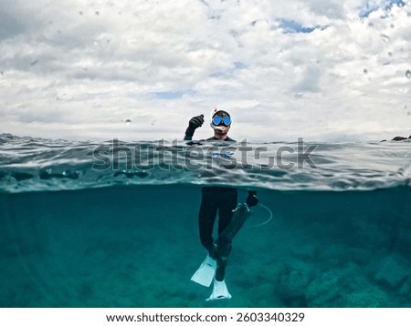 A diver waves from the water’s surface, enjoying the seamless connection between the underwater and above-water worlds.