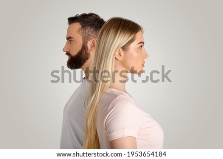 Divergent views, sexism and feminism, inequality, financial, social superiority, gender gap concept. Serious young guy and lady stand side by side and look in different directions, on gray background
