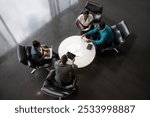 A diverse African group of professionals collaborate around a table, using laptops and tablets for a productive business meeting. The image conveys teamwork, strategy, and communication.