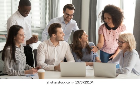 Diverse Ages Ethnicity Office Employees Sitting In Boardroom Looking At Pc Screen Laughing Have Fun At Coffee Break, During Business Meeting Or Training Funny Company Staff Interns And Boss Make Pause