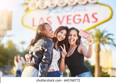 diverse all girl group of friends having fun taking selfies in front of welcome to las vegas sign