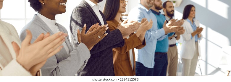 Diverse audience applauding at a public conference. Multiracial group of happy people smiling and clapping hands to express respect and gratitude to an interesting business lecturer. Header background - Powered by Shutterstock
