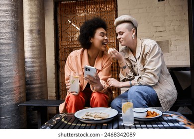 A diverse, beautiful couple of lesbians enjoying a meal together at a cafe. - Powered by Shutterstock