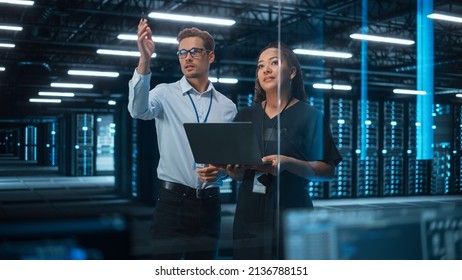 Diverse Big Data Center Server: Entrepreneur And IT Specialist Look At Laptop Screen And Talk. Information Technology Engineer And System Administrator Monitoring Web Services Cloud Solution Software