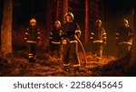 Diverse Brigade of Five Professional Firefighters Posing and Looking at Camera in a Forest Fire Situation. Multicultural Team Wearing Protective Clothing and Gear. Squad Leader Holding a Firehose.