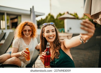 A diverse bunch of friends having a blast at a poolside gathering. They're laughing, sipping on drinks, and snapping selfies in the yard - Powered by Shutterstock