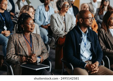 Diverse business audience sitting attentively in a workshop or conference setting, focusing on presentations and discussions. - Powered by Shutterstock