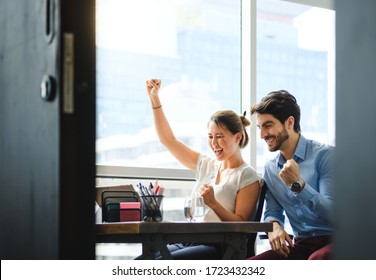 Diverse Business Couple Watching And Using Laptop Together, Asian And Caucasian Coworkers Cheer Good News And Winning, Having Fun Looking At Computer Screen.