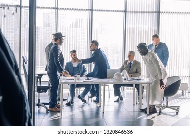 Diverse business executives discussing project sitting at conference table, multiracial partners talking about marketing plan at corporate briefing, african manager offering new idea at group meeting