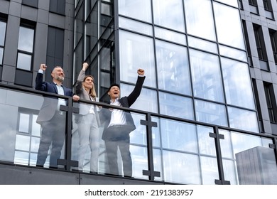 Diverse Business Group Of People Colleagues In Business Clothes Outside Office Building, Male And Female Employees Rejoice And Celebrate Victory Hold Hand Up And Smile Successful Team