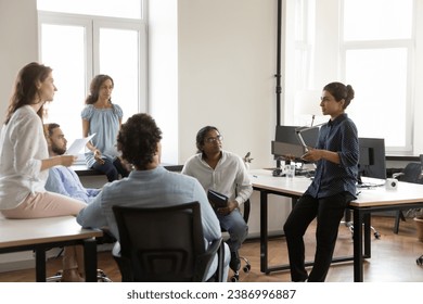 Diverse business group of serious employees negotiating on work project in office, sharing ideas for startup, listening to Indian female business leader. Company coach training interns - Powered by Shutterstock