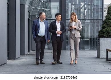 Diverse Business Group, Three Male And Female Workers Walking And Chatting Discussing Plans, Outside Office Building