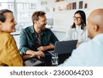 Diverse business people having a team meeting in an office. Group of happy business professionals sitting around a table and having a discussion.
