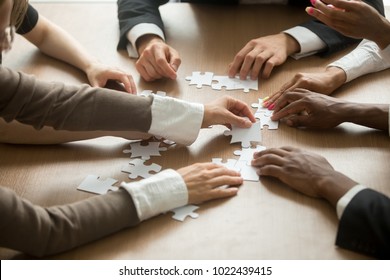 Diverse business people helping in assembling puzzle, cooperation in decision making, team support in solving problems and corporate group teamwork concept, close up view of hands connecting pieces - Shutterstock ID 1022439415
