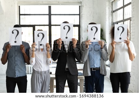 Diverse business people hiding faces behind papers sheets with question marks, standing in row in office. Identity and equality employee at work, candidates waiting for job interview, recruitment.
