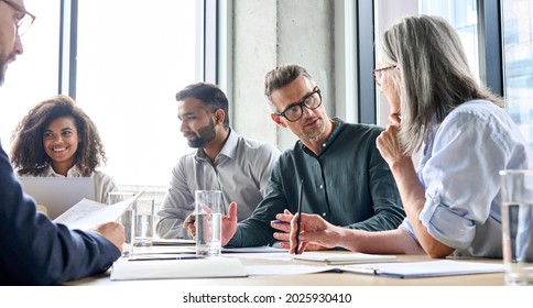 Diverse business people partners group negotiating at boardroom meeting.Multiethnic executive team discussing financial partnership agreement project strategy brainstorming sitting at table in office. - Powered by Shutterstock