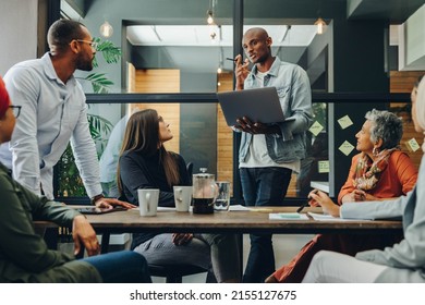 Diverse business professionals having a discussion during a meeting in a modern office. Team of multicultural businesspeople sharing creative ideas in an inclusive workplace. - Shutterstock ID 2155127675