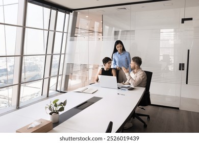 Diverse business project workgroup talking at laptop in meeting room workspace, discussing teamwork, cooperating on Internet startup, working together in contemporary workspace interior - Powered by Shutterstock