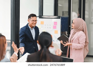 Diverse business team analyzing data and discussing strategies during an office meeting, using documents and a laptop - Powered by Shutterstock