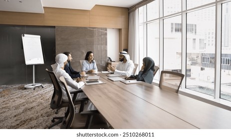 Diverse business team of Arab and European partners sitting at large meeting table in office boardroom, discussing company management, project analysis, contract. Wide banner shot with copy space - Powered by Shutterstock